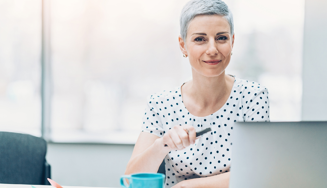 woman at desk with cup of coffee and computer