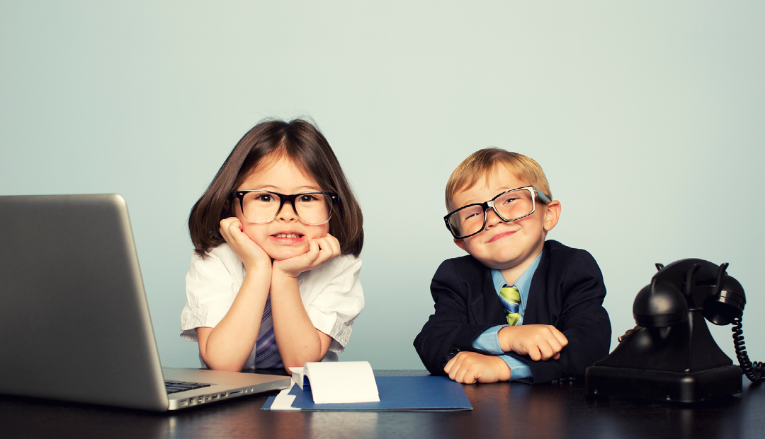 Two kids sitting behind office desk