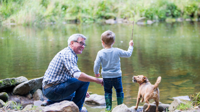 grandpa and grandson fishing on the water with small dog