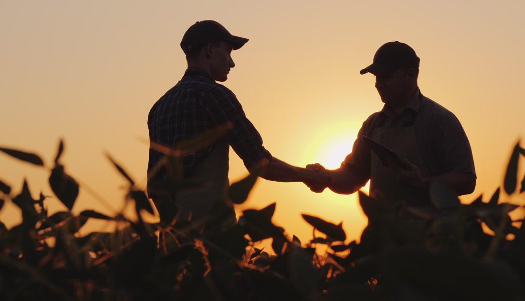 Farmer and Ag Banker standing in field shaking hands