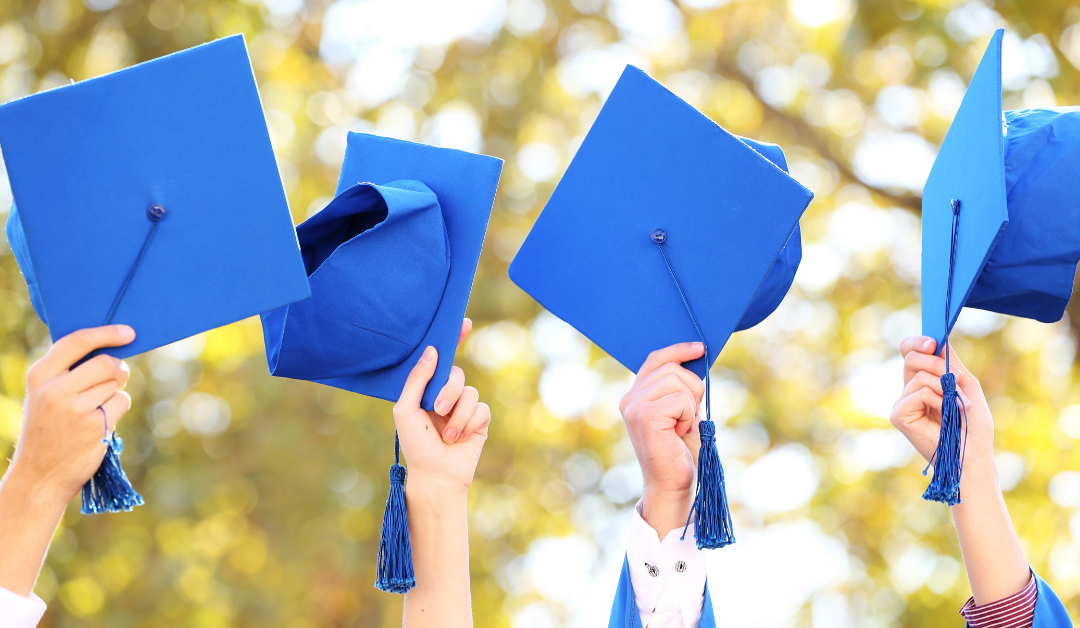 Students holding mortarboard hats in the air